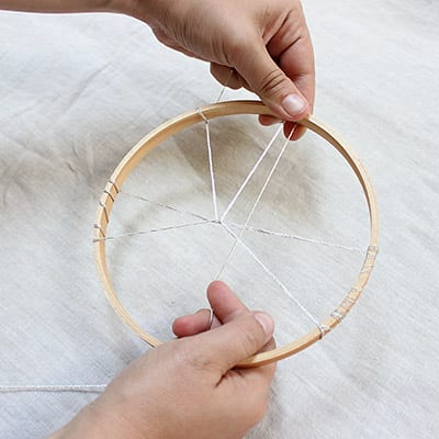 Hands holding dreamweaver weaving string around to create craft